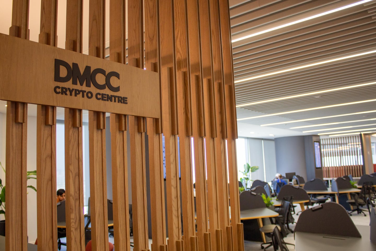 The DMCC Crypto Centre logo is juxtaposed to a co-working space.